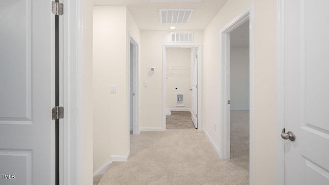 hallway featuring visible vents, baseboards, and light colored carpet