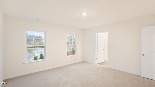 unfurnished room with baseboards, visible vents, and light carpet