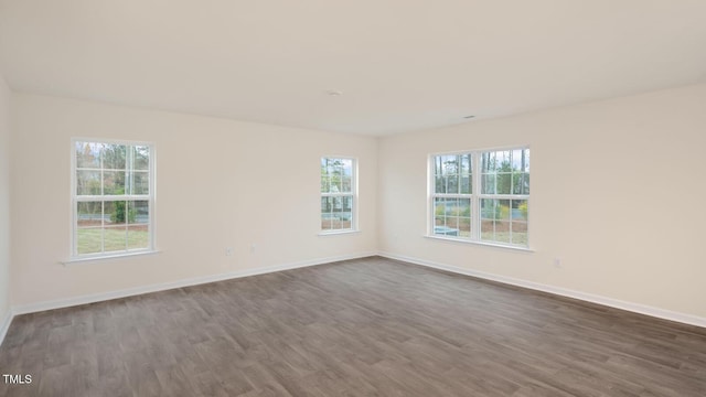 unfurnished room with baseboards and dark wood finished floors
