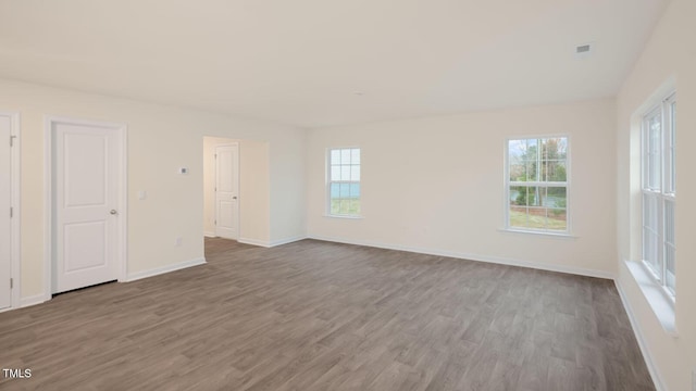 unfurnished room with plenty of natural light, baseboards, and wood finished floors