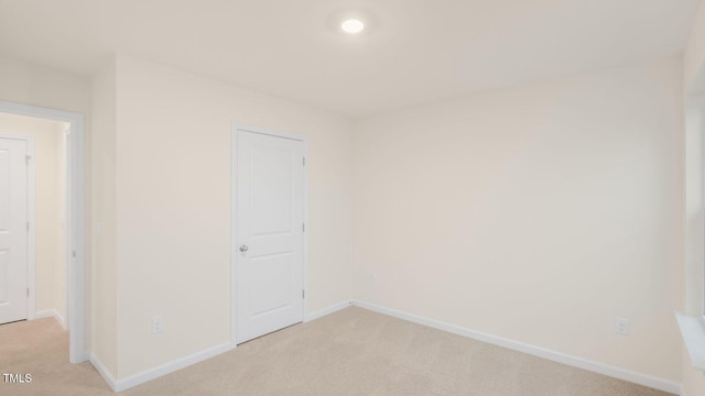unfurnished room with baseboards and light colored carpet