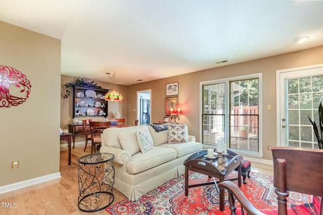 living room with baseboards, visible vents, and light wood-style floors