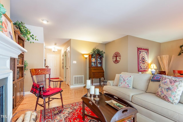living room featuring baseboards, visible vents, light wood-type flooring, and a fireplace