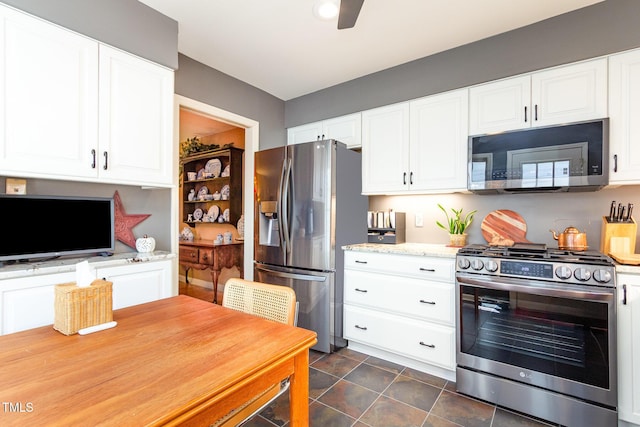 kitchen featuring light stone counters, ceiling fan, stainless steel appliances, and white cabinetry