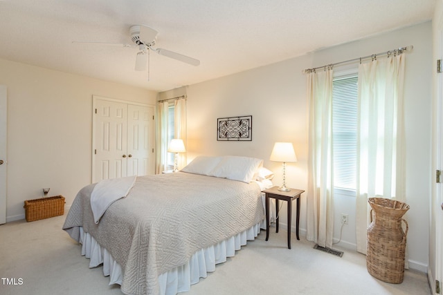 bedroom with baseboards, light colored carpet, visible vents, and a closet