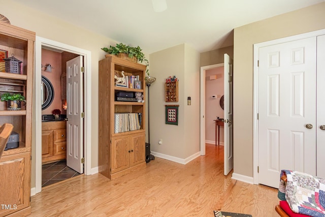 interior space featuring connected bathroom, baseboards, and light wood finished floors