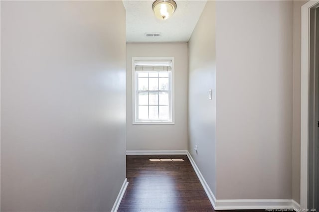 doorway featuring baseboards, visible vents, and dark wood finished floors