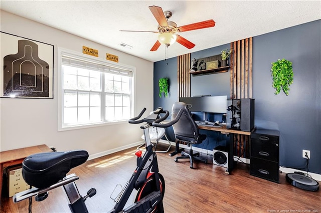 office featuring baseboards, ceiling fan, wood finished floors, and visible vents