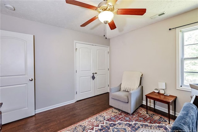living area featuring baseboards, a ceiling fan, wood finished floors, and visible vents