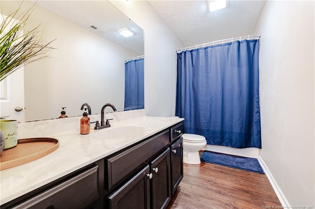 full bathroom featuring double vanity, visible vents, wood finished floors, a sink, and toilet