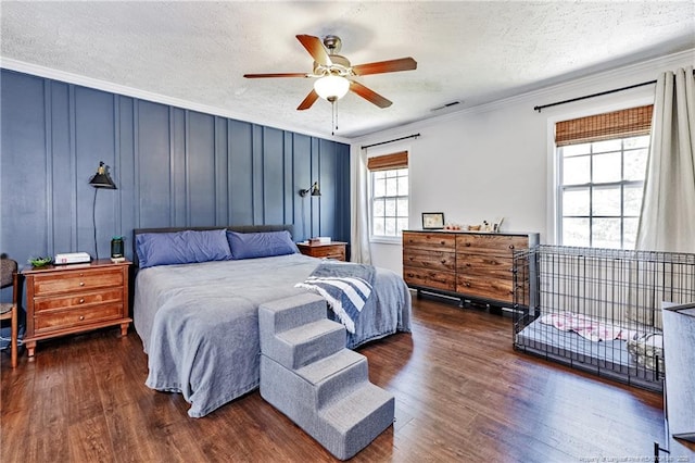 bedroom with ceiling fan, a textured ceiling, wood finished floors, visible vents, and ornamental molding
