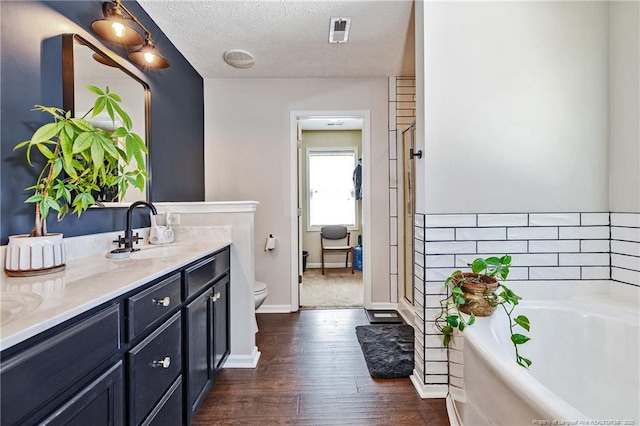 full bathroom with vanity, toilet, baseboards, wood finished floors, and a garden tub