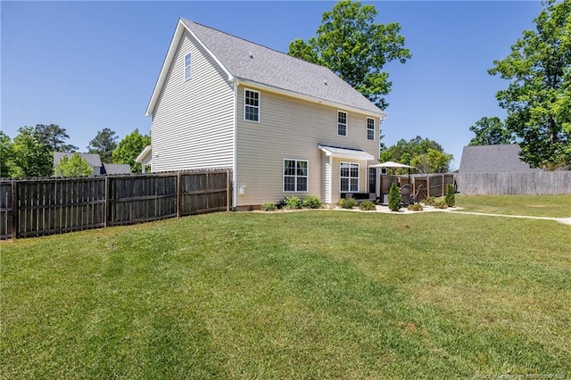 rear view of house featuring a lawn and a fenced backyard