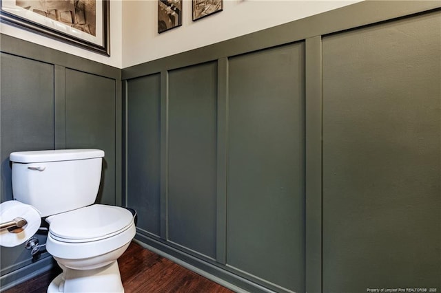 bathroom with a decorative wall, wood finished floors, and toilet