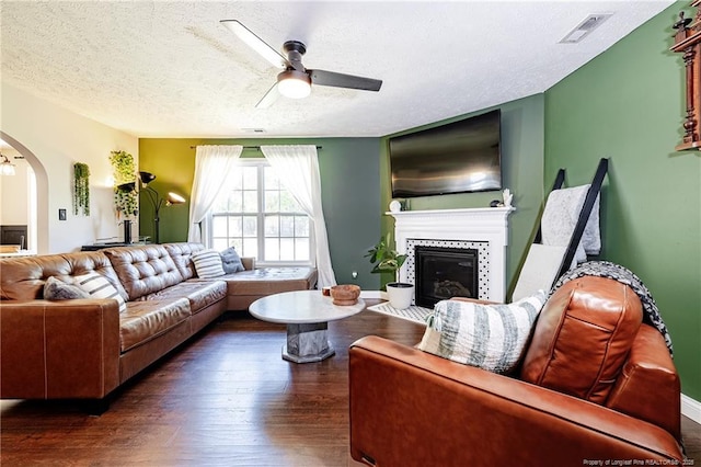 living area with visible vents, wood finished floors, a textured ceiling, arched walkways, and a ceiling fan