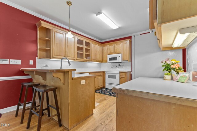 kitchen featuring a peninsula, white appliances, glass insert cabinets, a kitchen breakfast bar, and light wood finished floors