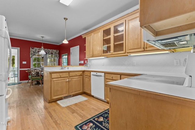 kitchen featuring white dishwasher, light wood-style flooring, a peninsula, decorative backsplash, and glass insert cabinets