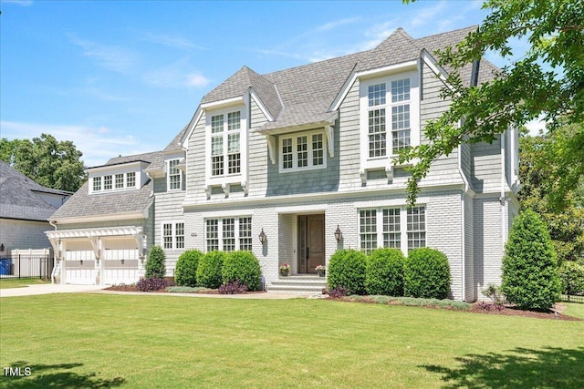shingle-style home with a front lawn, driveway, and a garage