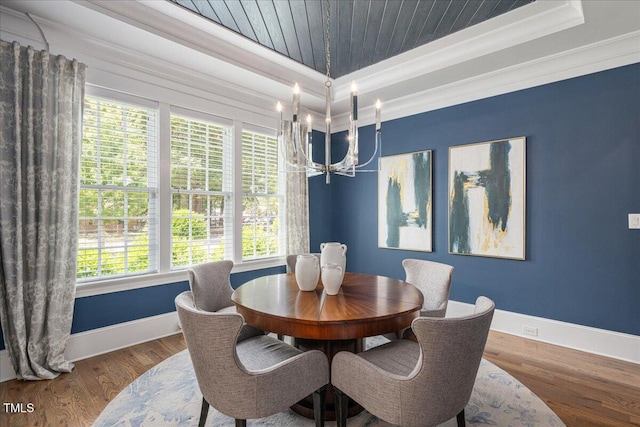 dining space featuring crown molding, baseboards, a tray ceiling, a chandelier, and wood finished floors