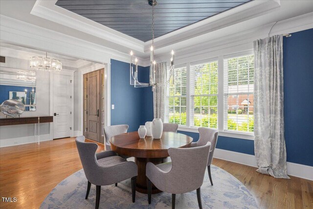 dining room featuring a chandelier, a raised ceiling, crown molding, and baseboards