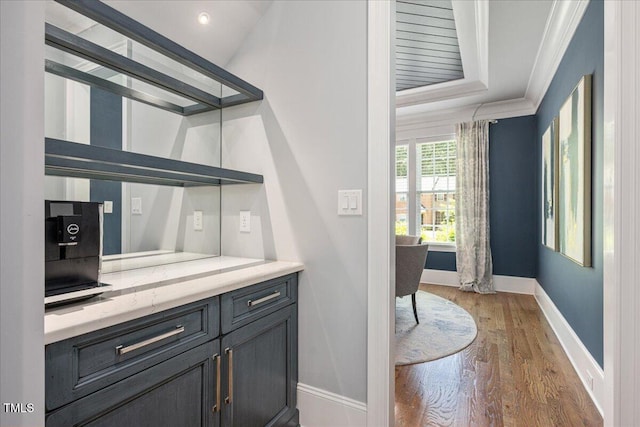 bar featuring baseboards, ornamental molding, and light wood-type flooring