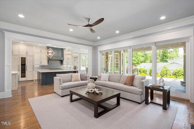 living area with a ceiling fan, recessed lighting, wood finished floors, and ornamental molding