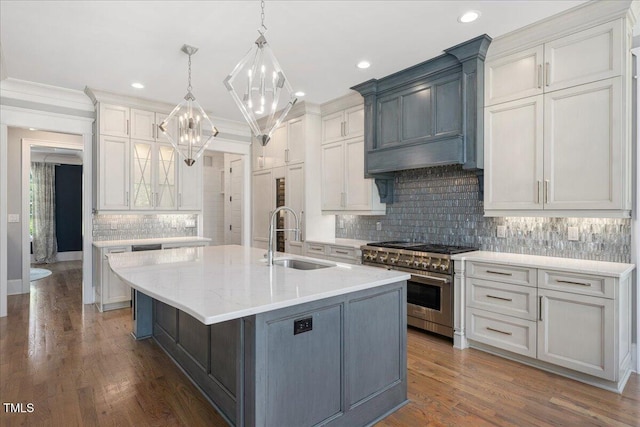 kitchen with high end range, a sink, a chandelier, backsplash, and premium range hood