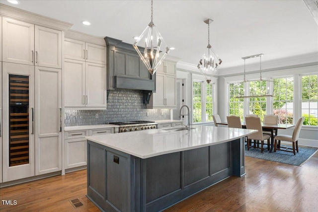 kitchen featuring a sink, healthy amount of natural light, a chandelier, tasteful backsplash, and ornamental molding