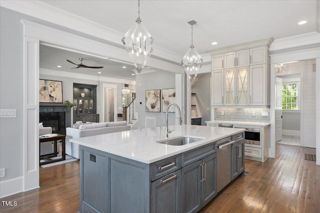 kitchen featuring a sink, white cabinetry, a glass covered fireplace, dishwasher, and crown molding