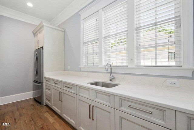 kitchen featuring a sink, freestanding refrigerator, ornamental molding, light stone counters, and dark wood-style floors