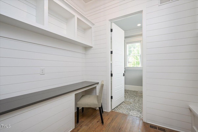 corridor with a desk, wood finished floors, and baseboards