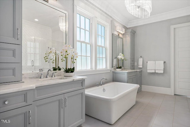 bathroom with ornamental molding, a chandelier, tile patterned flooring, two vanities, and a freestanding tub