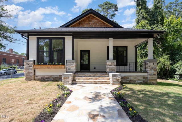 craftsman-style house with a front lawn, covered porch, and stone siding