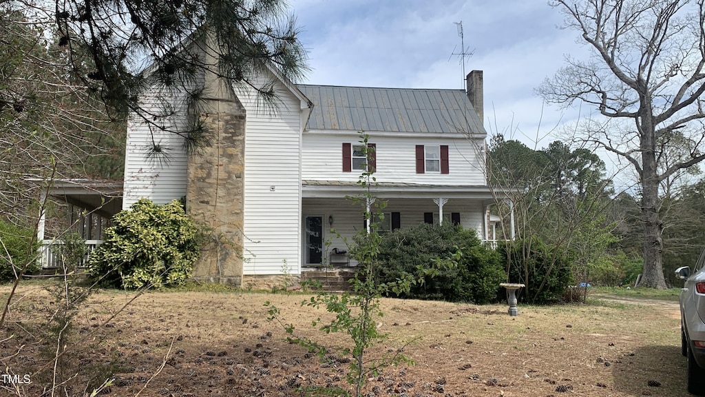 view of front of home featuring covered porch, metal roof, and a chimney