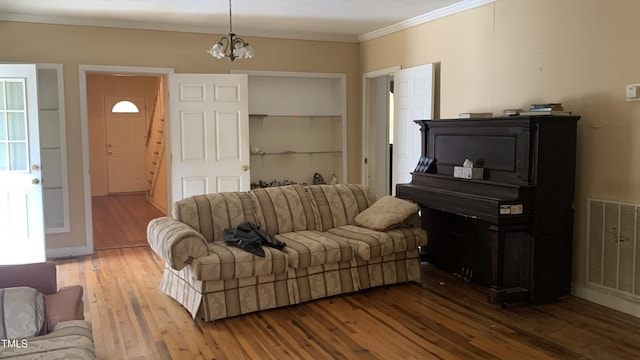living room featuring visible vents, ornamental molding, a chandelier, and hardwood / wood-style flooring