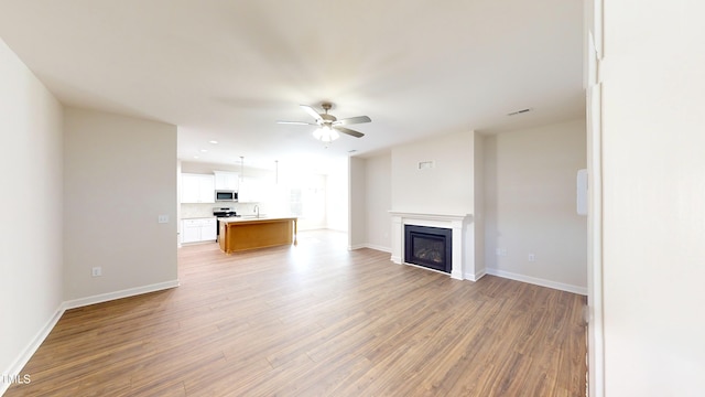 3725 Huntcliff Dr, La Grange, NC 28551 - unfurnished living room with light wood-type flooring, a ceiling fan, baseboards, and a glass covered fireplace