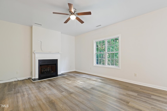 3223 Polite Ln, Raleigh, NC 27610 - unfurnished living room featuring wood finished floors, a fireplace with raised hearth, ceiling fan, and baseboards