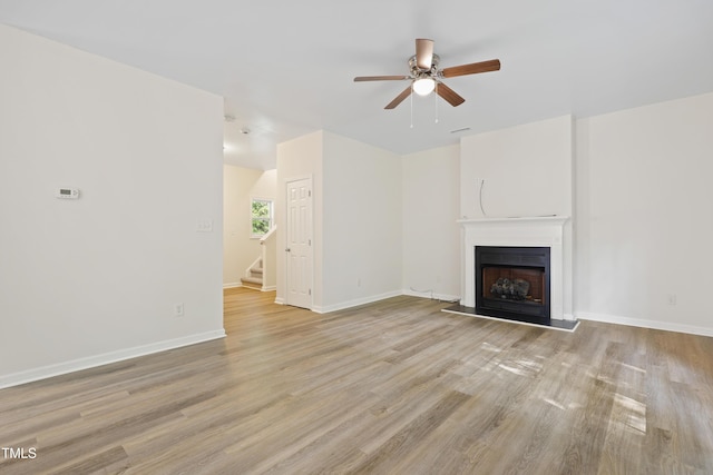 3223 Polite Ln, Raleigh, NC 27610 - unfurnished living room featuring ceiling fan, light wood finished floors, stairs, and a fireplace with raised hearth
