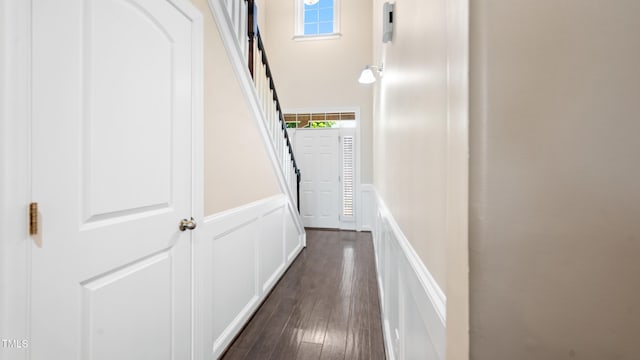 hall with stairs, a decorative wall, a wainscoted wall, and dark wood-type flooring