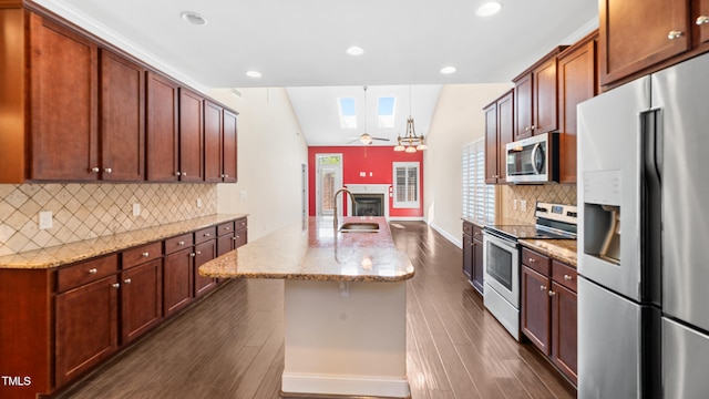 kitchen with a ceiling fan, stainless steel appliances, a fireplace, dark wood finished floors, and tasteful backsplash