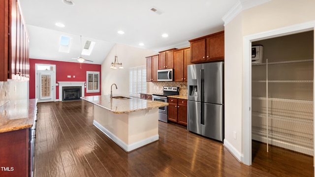 kitchen with a sink, stainless steel appliances, tasteful backsplash, vaulted ceiling with skylight, and a fireplace