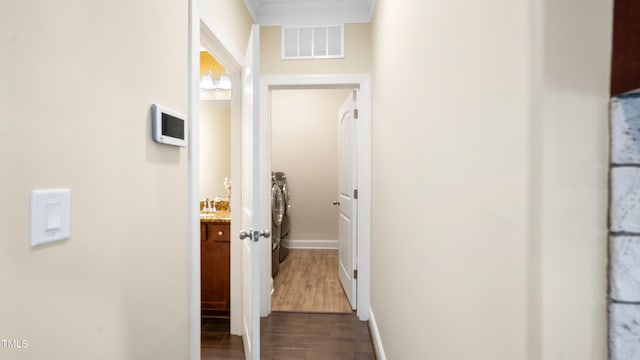 corridor with baseboards, washer and dryer, visible vents, and dark wood-type flooring