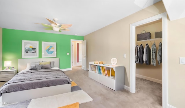 bedroom featuring a closet, a walk in closet, carpet floors, baseboards, and ceiling fan