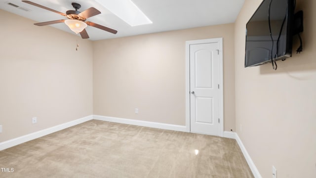 empty room featuring a ceiling fan, carpet, baseboards, visible vents, and a skylight