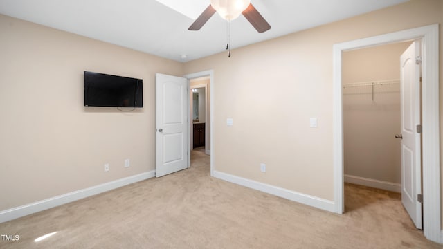 unfurnished bedroom featuring a closet, ceiling fan, a spacious closet, carpet floors, and baseboards