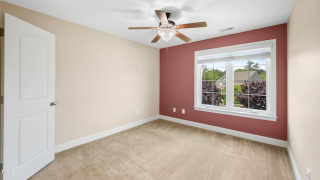 empty room featuring light colored carpet, baseboards, a ceiling fan, and visible vents