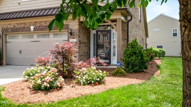 view of exterior entry featuring concrete driveway, an attached garage, and brick siding