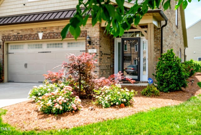 exterior space featuring concrete driveway, a garage, a standing seam roof, and brick siding