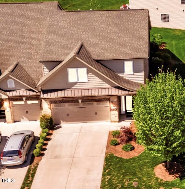 view of front of property featuring concrete driveway, brick siding, roof with shingles, and a garage