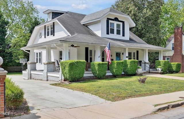 view of front of property featuring a shingled roof, a front lawn, and covered porch